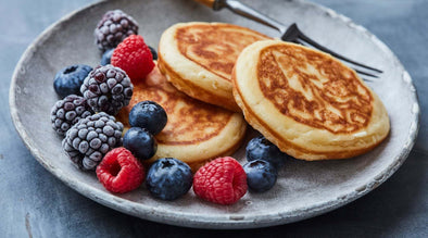 Can dogs eat pancakes - Image is three pancakes on a plate with a selection of berries to the side.