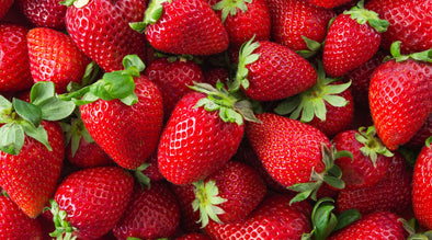 Can dogs have strawberries - Image is a pile of red, juicy strawberries that still have their green stem attached.